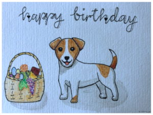 Karte mit der Zeichnung eines fröhlich hechelnden Jack-Russel-Terriers, der neben einem Geschenkkorb mit Schokolade, bemalten Ostereiern, Trauben und einem Lutscher steht; darüber steht der Schriftzug 'happy birthday'